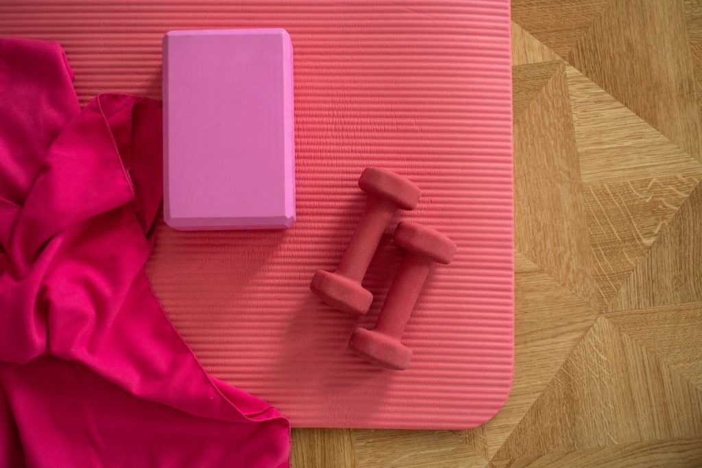<pink yoga mat, block, weights, and blanket>