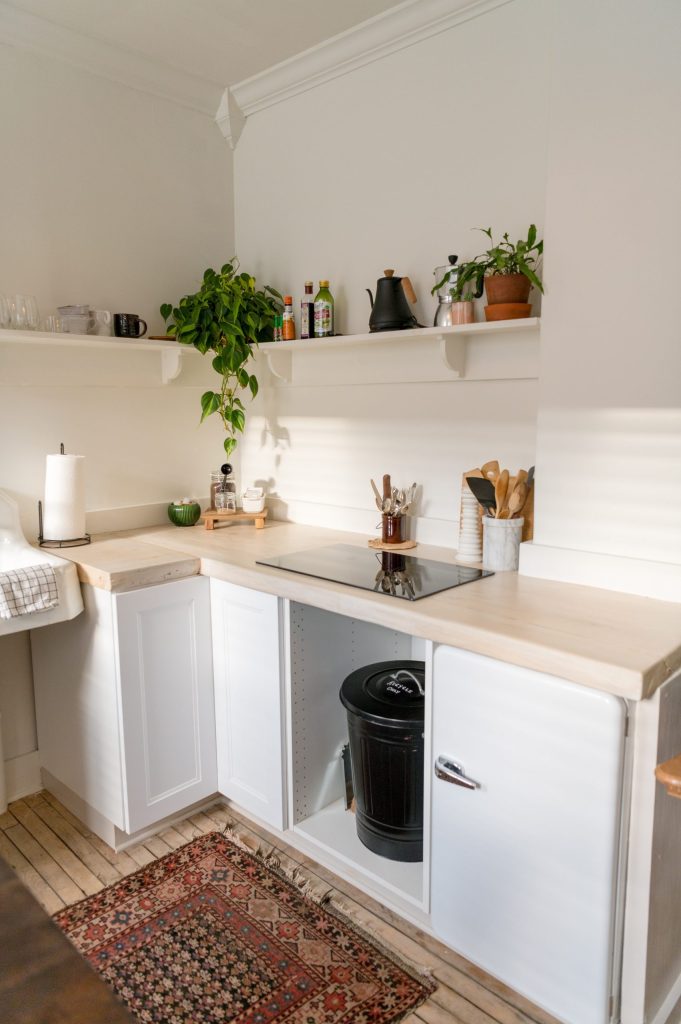 (alt-text: A white-walled kitchen uses vertical space for minimalist decluttering to give every item a home.) 