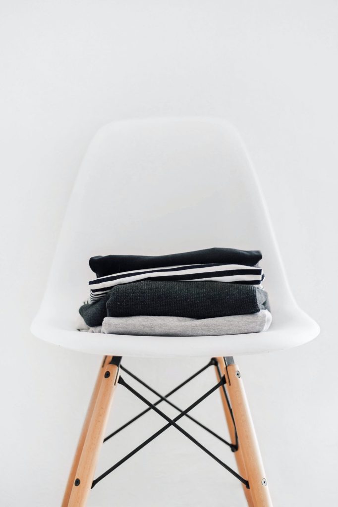 (alt-text: A white chair holds a pile of black, white, and gray clothes) 
