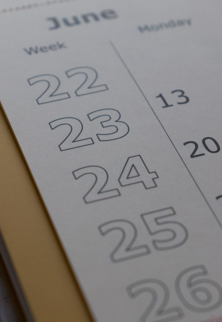 A decluttering calendar is open to the month of June on a wooden desktop