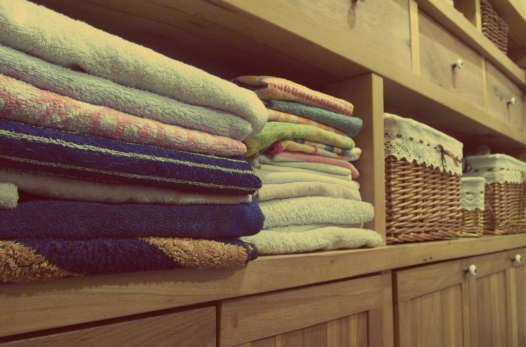 A closet holds organised towels and baskets as a way to declutter a house.