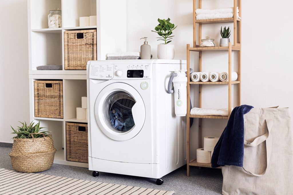  A front load washing machine sits in a laundry room that uses boxes and shelving to keep it clutter-free