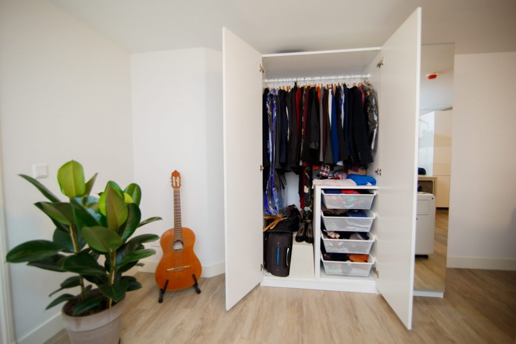A closet is open with clothes hanging in it after being organised using a decluttering schedule.