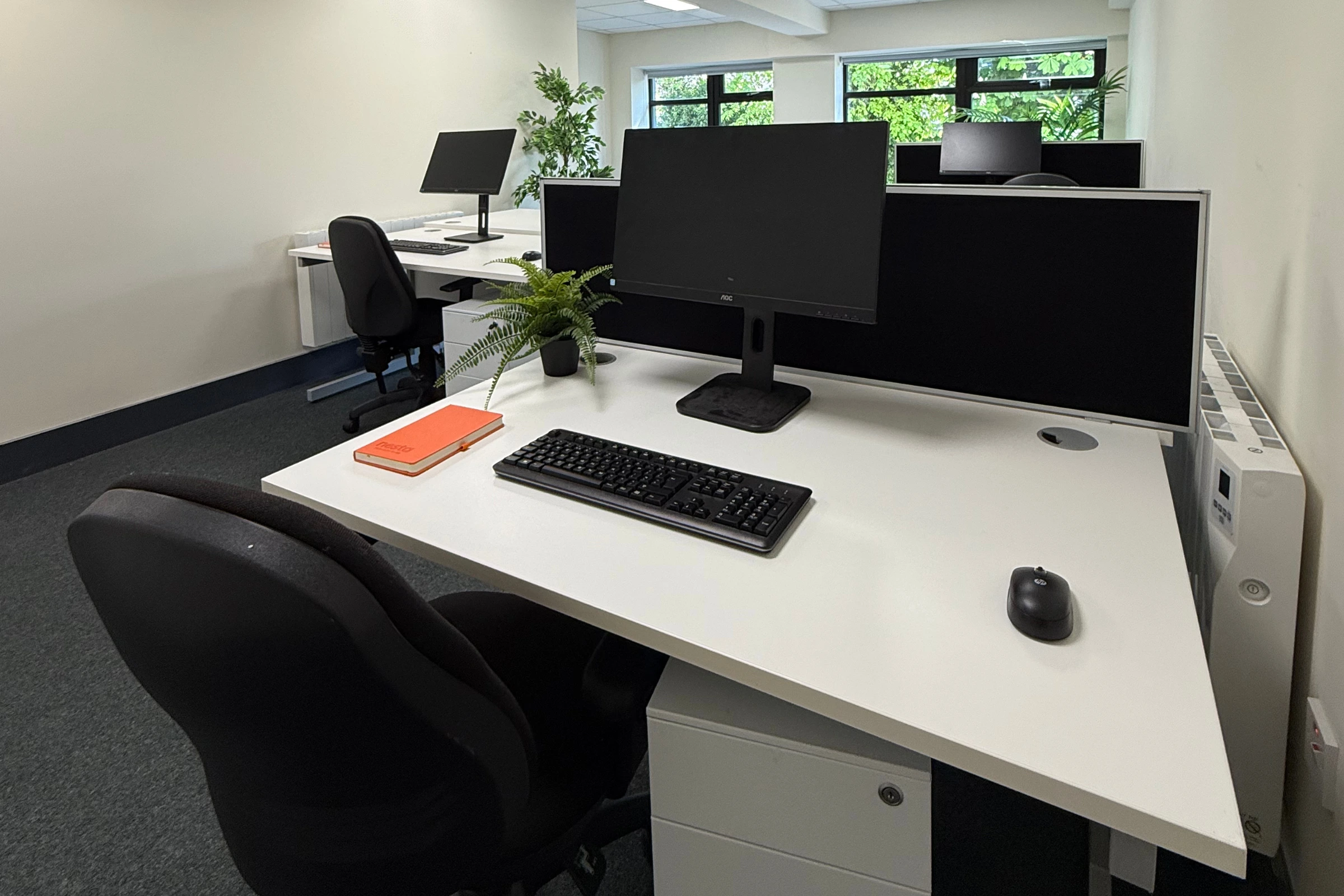 a Windowed Office with desktop, mouse, keyboard notebook and chair.