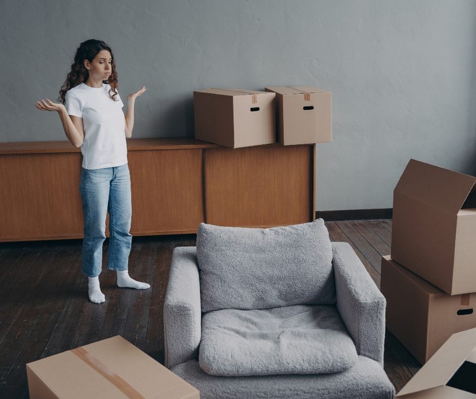 Moving home life event - Nesta woman moving out of her apartment surrounded by boxes and furniture