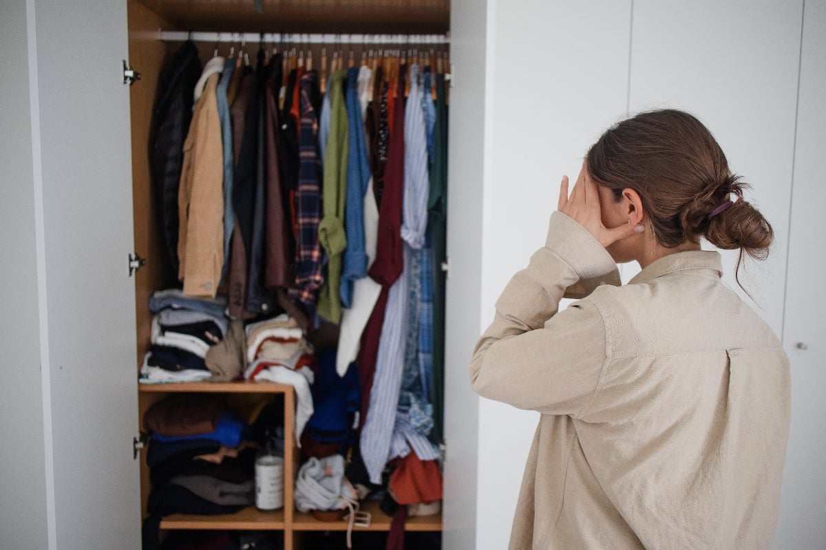 5 - Nesta Woman stressed looking into cluttered wardrobe full of clothes