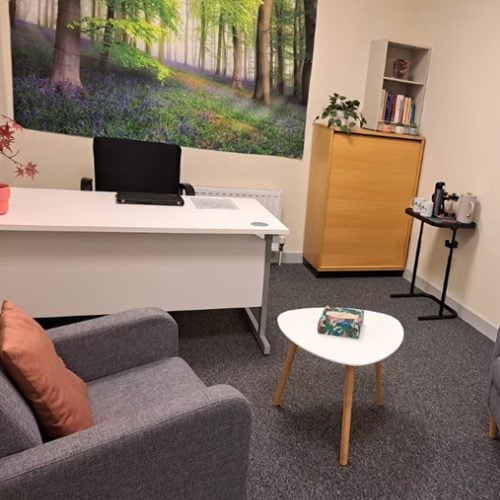 Serviced offices Sandyford - Nesta - Nesta Reception-like office lounge with white desk and laptop, forest mural, gray sofa, and a round coffee table
